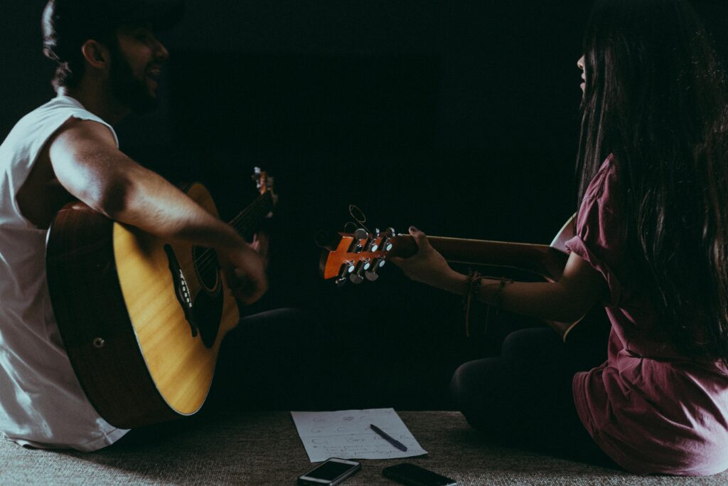 Musicians collaborate with acoustic guitars in a cozy, dimly lit setting.